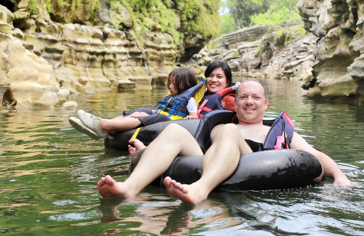 happy family floating on inflatable tube in river during vacation