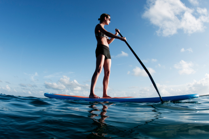 young woman in bikini and sunglasses on a paddleboard